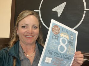 Lisa Johnson seated, holding poster describing the attributes of a person who is an Enneagram 8 leadership type.